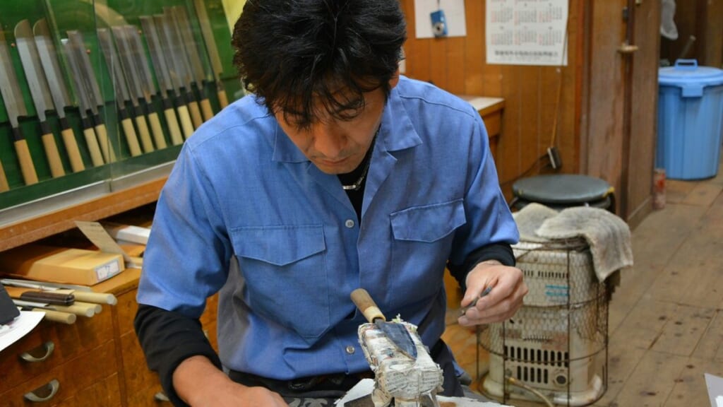 工房で包丁に名入れをする職人